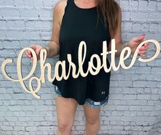 a woman standing in front of a brick wall holding up a sign that says charlotte