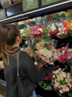 a woman is looking at flowers in a store