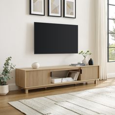 a living room with a large flat screen tv mounted to the wall and two framed pictures on the wall