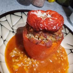 two stuffed tomatoes sit on top of each other in a bowl filled with tomato sauce