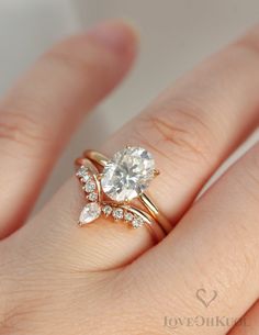 a woman's hand with a diamond ring on top of her finger and an engagement band