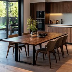 a dining room table and chairs in front of an open kitchen area with sliding glass doors