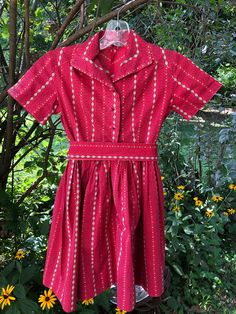 1940s girls red cotton daisy stripe dress: This little red print dress appears to be a 6-8. It is in a lovely shade of red with little white and gold daisy stripes. It is collared and has a natural waistline. The skirt is gathered. The back has a western cut. It buttons front center with red buttons. It has a sash lined in gold Measurements: Shoulder to shoulder 13 in. Chest 30 in. Waist23 in. Length 29 in. Red Vintage Short Sleeve Dress For Spring, Red 1950s Style Spring Dress, Red Short Sleeve Vintage Dress For Spring, Red 1950s Spring Dresses, Red Cotton Vintage Summer Dress, Red Cotton Vintage Dress, Vintage Red Short Sleeve Dress, Vintage Cotton Collared Dress, Vintage Collared Cotton Dress