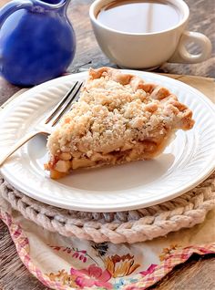 a piece of pie sitting on top of a white plate next to a cup of coffee