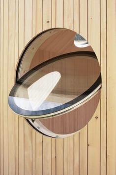 a circular mirror hanging on the side of a wooden wall