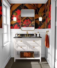 a bathroom with floral wallpaper and white vanity, gold faucet, and mirror