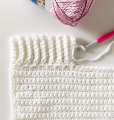 the crochet pattern is next to yarn and a ball of pink thread on a white surface