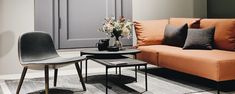 a living room with an orange couch and coffee table in front of a gray door