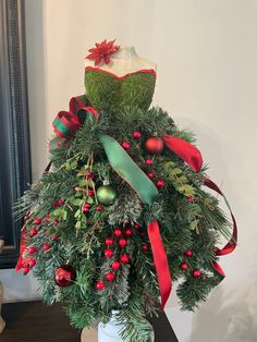 a christmas tree with red and green ornaments on it's top, sitting in a white vase