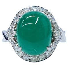 This exquisite ring features a captivating oval-shaped cabochon Colombian emerald, weighing 4.85 carats. The emerald's rich green color, characteristic of Colombian emeralds, is complemented by a sparkling halo of diamonds, totaling 0.44 carats. The ring is crafted in 18k white gold, providing a luxurious and timeless setting for these precious gemstones. The ring showcases a unique and elegant design that highlights the beauty of the Colombian emerald. The oval cabochon cut of the emerald creates a smooth, rounded surface that reflects light beautifully. The diamond halo adds a touch of sparkle and brilliance, enhancing the emerald's color and overall appeal. The 18k white gold setting provides a luxurious and timeless backdrop for the gemstones, complementing their natural beauty. Except Colombian Emerald Ring, Emerald Diamond Ring, White Gold Set, Colombian Emeralds, Emerald Color, Rich Green, Modern Ring, Emerald Stone, Gold Diamond Rings