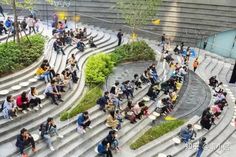 many people are walking up and down the stairs in an open area with concrete steps