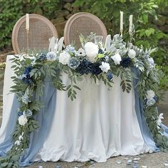 the table is decorated with blue and white flowers, greenery and candles for an elegant touch