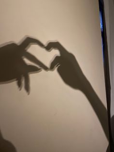 the shadow of two hands making a heart shape