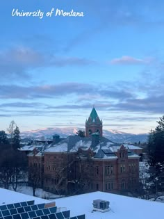 the university of montana building is surrounded by snow and trees with mountains in the background