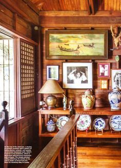 a room filled with lots of vases and pictures on the wall next to a wooden banister