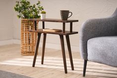 a small table with a cup on it next to a chair and potted plant