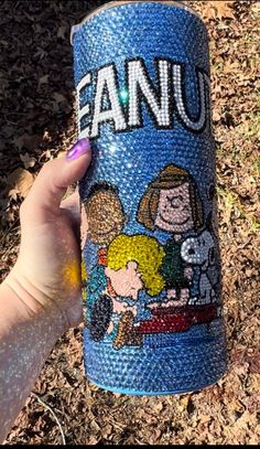 a hand holding up a blue can with cartoon characters on it and the words fanu painted on it