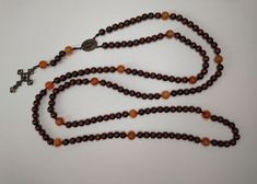 "Handmade 15 decade rosary in beautiful 7mm wood beads and 10mm calcite beads. This beautiful peace evokes the humility and simplicity of Franciscan monks, while the blazing orange calcite was inspired by the tongues of fire that descended on Christ's disciples.  Strung together with 1mm nylon cord, the rosary should withstand up to 10kg of pressure, making it not as delicate as it looks.  Measures 80cm / 31.5\"  Handmade in France Chapelet de 15 dizaines fait à la main en belles perles de bois Handmade Brown Rosary For Healing, Spiritual Brown Rosary For Healing, Brown Rosary Bracelet With 8mm Beads For Meditation, Bohemian Brown Rosary With 8mm Beads, Amber Rosary With 8mm Beads In Spiritual Style, Amber Rosary With 8mm Beads, Spiritual Style, Amber Rosary With 8mm Beads, Spiritual Amber Rosary With 8mm Beads, Brown Beaded Spiritual Rosary