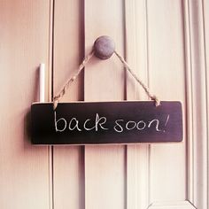 a sign that says back soon hanging on a door with a ball in the background