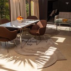 a glass table with chairs around it in the middle of a living room filled with furniture