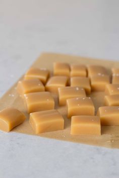 some pieces of cheese are sitting on a piece of parchment paper and ready to be cut into cubes