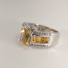 The Scapolite Gemstones Are A Lovely Honey Yellow. The Oval Cut 7x9mm Genuine Scapolite Is 1.5 Carats. The Marialite Center Stone Is Flanked By Eight 2x4mm Citrine Baguettes Gemstones. (1 Cttw). There Are 38 Genuine 1.2mm Round Cut White Topaz Accents (0.4 Cttw). The Ring Setting Is A Highly Polished Band Style. This Stunning Platinum Over Sterling Silver Ring Will Be A Favorite. Platinum Adds Luster And Protection. New Without Tags. Gift Box Included. Yellow Multi-stone Sapphire Ring, Yellow Multi-stone Round Gemstones, Fine Jewelry Yellow Multi-stone Rings, Yellow Multi-stone Fine Jewelry, Yellow Diamond Fine Jewelry Gemstones, Fine Jewelry Yellow Diamond Gemstones, Yellow Gemstones With Accents Fine Jewelry, Oval Yellow Sapphire Jewelry With Center Stone, Yellow Round Diamond Gemstones