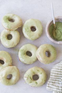 doughnuts with green icing on a table next to a bowl of powdered sugar