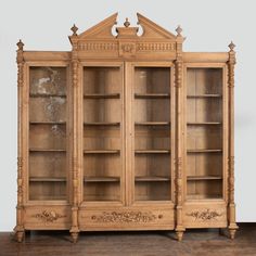 an old wooden bookcase with glass doors and carvings on the front, sitting on a hard wood floor