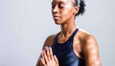 a woman with her hands folded in prayer position while wearing a black tank top and yoga pants