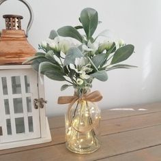 a vase filled with flowers sitting on top of a wooden table next to a lantern