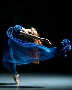 a woman with red hair and blue dress is dancing in the dark while wearing ballet shoes