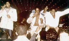 three men in white jackets are dancing on stage