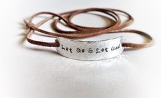 "Wear your daily affirmations and inspirational words on your wrist to remind yourself of what is most important to you every day. :) This leather wrap bracelet features the phrase \"Let Go and Let God\", hand stamped onto hammered aluminum. The soft brown faux suede leather cord is approximately 36\" long and can usually wrap around the wrist 2 times. The. Just tie a loose knot or two in the back to secure and you are good to go! You can have this bracelet with or without the tiny cross at the Inspirational Handmade Bracelets For Everyday, Inspirational Handmade Bracelet For Everyday, Inspirational Engraved Bracelets For Everyday, Inspirational Stamped Bracelets For Friendship, Everyday Inspirational Engraved Bracelets, Inspirational Engraved Everyday Bracelets, Inspirational Adjustable Stamped Bracelets, Spiritual Adjustable Hand Stamped Bracelets, Adjustable Spiritual Hand Stamped Bracelets