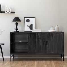 a black cabinet sitting on top of a hard wood floor next to a table with two lamps