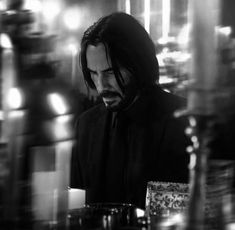 a man with long hair wearing a suit and tie sitting at a table in front of candles