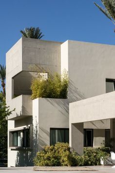 an apartment building with plants growing on the balconies and trees in front of it