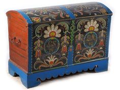 an old painted wooden chest with decorative designs on the front and sides, sitting upright against a white background