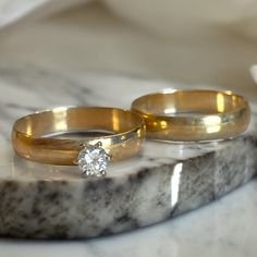 two wedding rings sitting on top of a marble slab