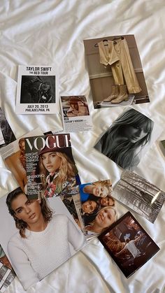 many magazines and pictures are spread out on a bed sheet with white sheets in the background