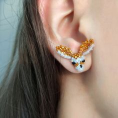 a close up of a person's ear with beaded animal earrings on it