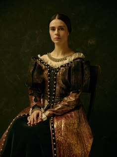 a woman sitting in a chair wearing a dress with pearls on the neck and sleeves