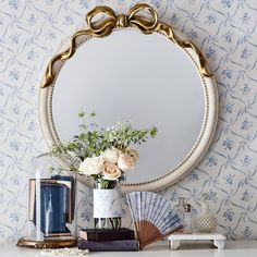 a mirror sitting on top of a dresser next to a vase with flowers