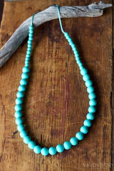 a blue beaded necklace sitting on top of a wooden table