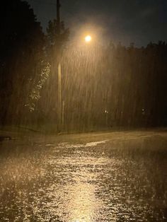 a street light shines brightly in the rain at night, as it rains down