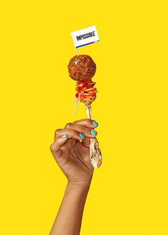 a woman holding up a lollipopo on top of a stick with the word impossible written on it