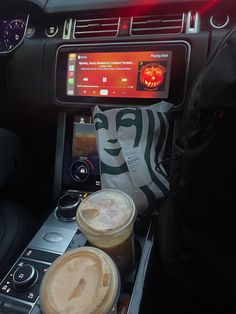 two cups of coffee sitting on top of a car dashboard next to a drink machine