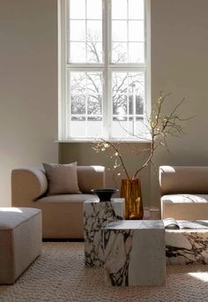 a living room filled with furniture and a vase on top of a table in front of a window