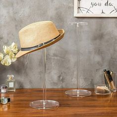 a hat is sitting on top of a clear stand next to other items and flowers