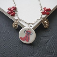 Add a one of a kind piece to your jewelry collection with our handmade polymer clay charm necklace! Each necklace is handmade to order. The necklace features a mix of charms made from high-quality polymer clay coated in resin and silver colored charms. This boot and bow charm necklace contains silver cowgirl hat charms, red clay bows, and a pendant with a red cowgirl boot graphic. Features a lobster clasp closure. Every necklace is handmade from start to finish! Polymer Clay Charm Necklace, Clay Charm Necklace, Silver Cowgirl, Hat Charms, Red Cowgirl Boots, Cowgirl Boot, Cowgirl Hat, Cowgirl Hats, Polymer Clay Charms