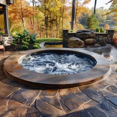 an outdoor hot tub surrounded by stone steps and trees with fall foliage in the background